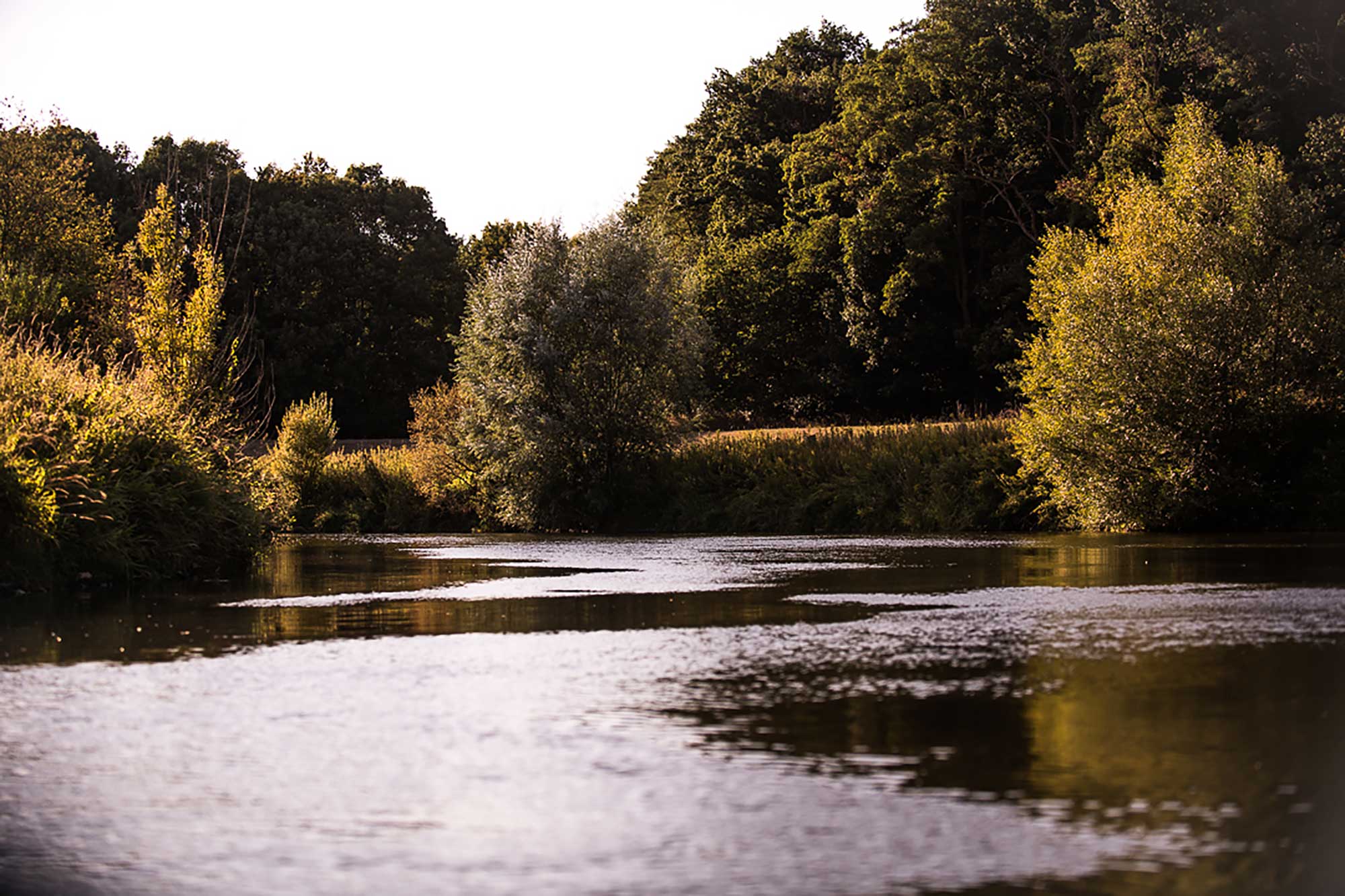Blick auf die Lippe bei schwächer werdender Sonne mit Bäumen im Hintergrund – aufgenommen während einer Kanutour von Dorsten nach Schermbeck, vor den Stromschnelle Blick auf die Lippe bei schwächer werdender Sonne mit Bäumen im Hintergrund – aufgenommen während einer Kanutour von Dorsten nach Schermbeck, vor den Stromschnelle